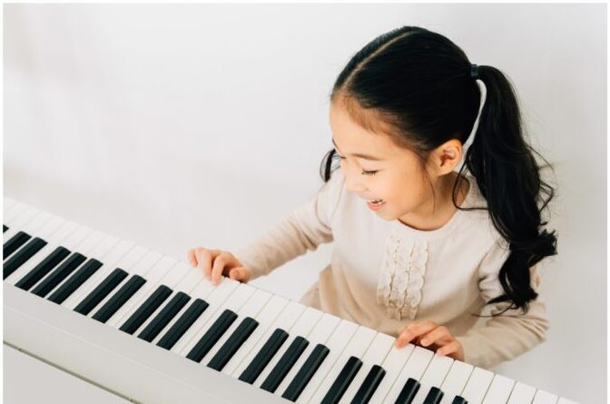 A little girl playing the piano with headphones on.