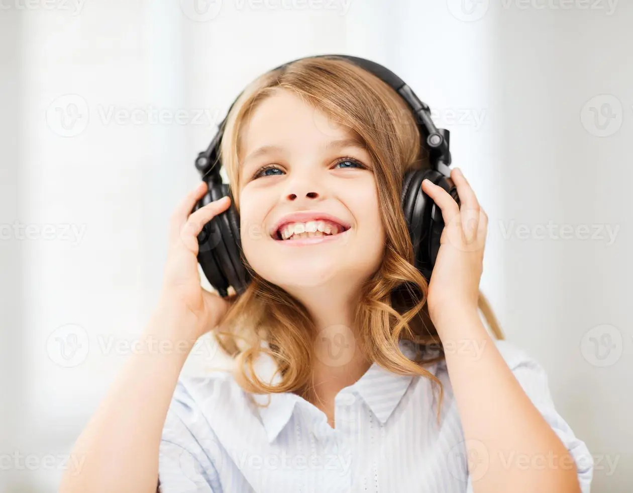 A girl with headphones is smiling for the camera.