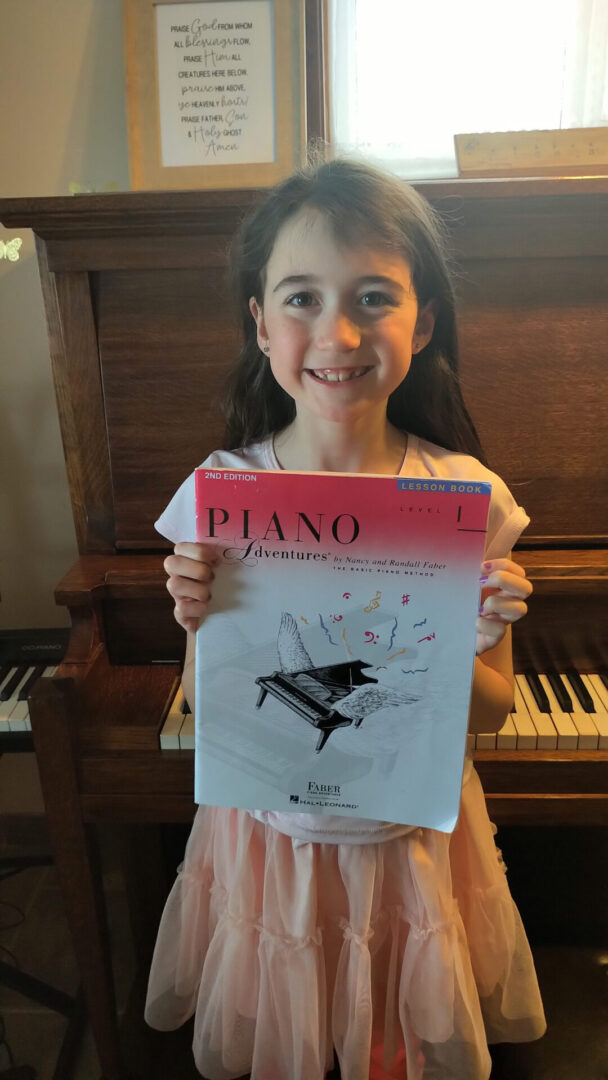 A girl holding up an old piano book.